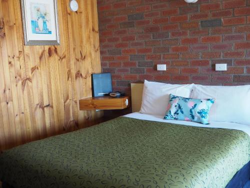 a bedroom with a bed and a brick wall at Country Road Motel St Arnaud in Saint Arnaud