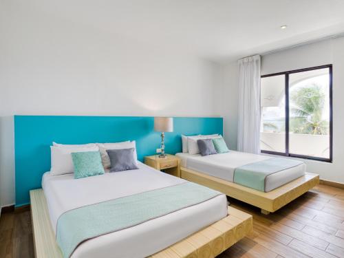 two beds in a room with blue and white at Hotel Ojo De Agua in Puerto Morelos
