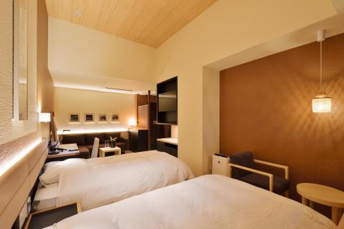 a hotel room with two beds and a desk at THE CHELSEA BREATH in Takamatsu