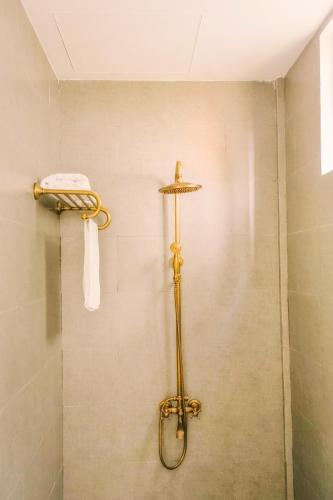 a shower in a bathroom with a towel on the wall at Tò Vò Hostel Huế in Hue