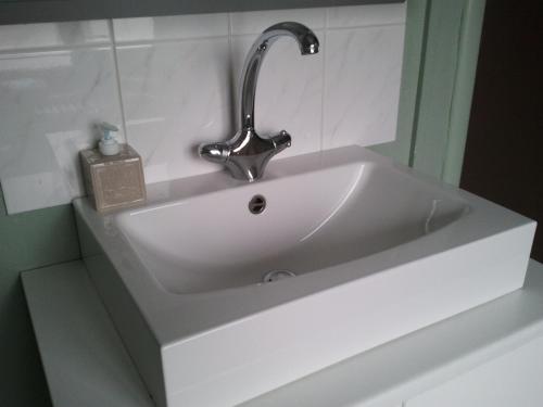 lavabo blanco con grifo en el baño en Hotel Duinekeuntje en Ostende