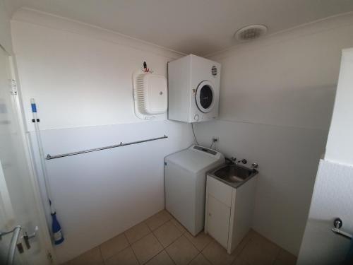 a small bathroom with a washing machine and a sink at Ocean Beach Chalet 18 in Jurien Bay