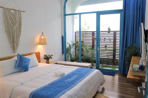 a bedroom with a large bed and a large window at Tò Vò Hostel Huế in Hue