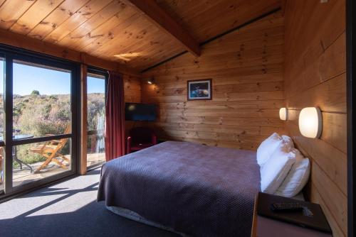 a bedroom with a bed and a large window at Skotel Alpine Resort in Whakapapa Village