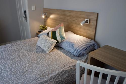 een slaapkamer met een bed met een houten hoofdeinde en kussens bij Carnarvon Lodge Kirribilli, Sydney in Sydney