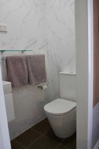 a white bathroom with a toilet and a towel at Carnarvon Lodge Kirribilli, Sydney in Sydney