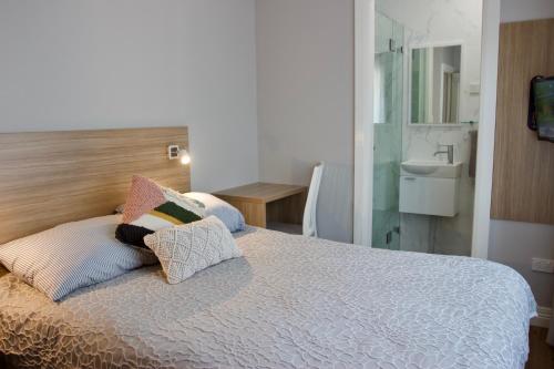 a bedroom with a bed with pillows and a sink at Carnarvon Lodge Kirribilli, Sydney in Sydney