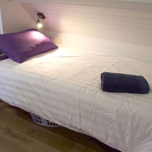 a large white bed with a purple pillow on it at Carnarvon Lodge Kirribilli, Sydney in Sydney