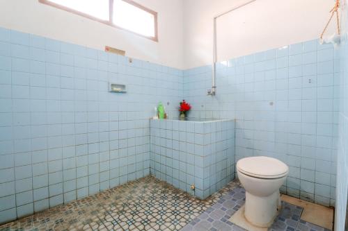 La salle de bains est pourvue de toilettes et de murs carrelés bleus. dans l'établissement Adil Jaya Homestay, à Yogyakarta