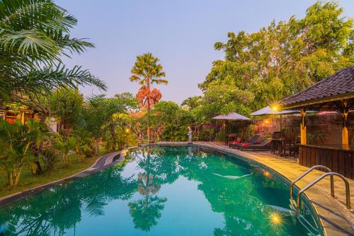 a large swimming pool in a yard with trees at Pondok Wisata Sartaya 2 in Lovina