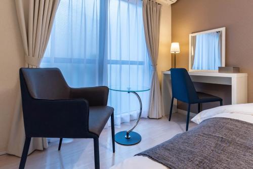 a hotel room with a bed and two chairs and a desk at Tino Anastasia in Osaka