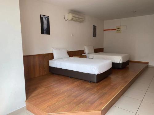 two beds sitting in a room with wood floors at Swan Garden Hotel in Pasir Gudang