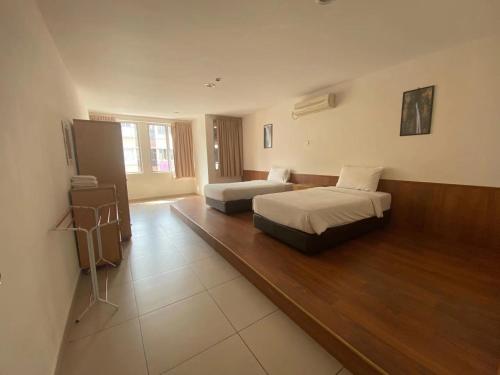 a large room with two beds and a table at Swan Garden Hotel in Pasir Gudang