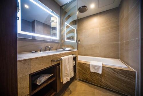 a bathroom with a tub and a sink at Ramada Encore by Wyndham Busan Station in Busan