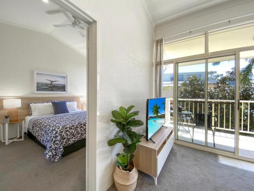 a bedroom with a bed and a large window at Seashells Apartments Merimbula in Merimbula