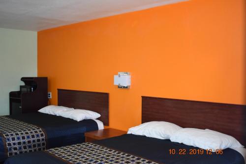 Habitación de hotel con 2 camas y pared de color naranja en Belmont Motel en Roswell