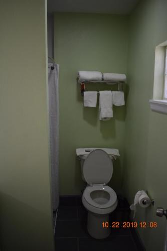 La salle de bains est pourvue de toilettes et de serviettes murales. dans l'établissement Belmont Motel, à Roswell