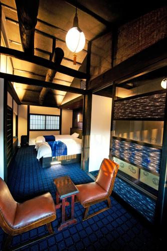 a hotel room with a bed and two chairs and a table at Tsuyukusa-an in Kyoto