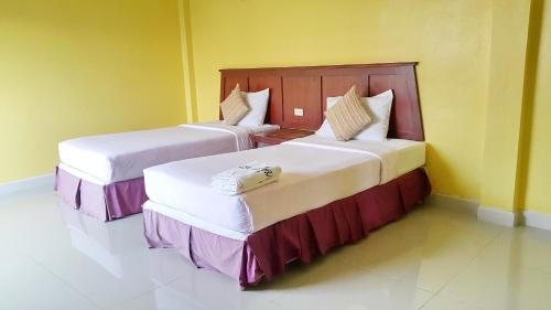 春蓬Sri Chumphon Hotel的一间黄色墙壁的房间里有两张床