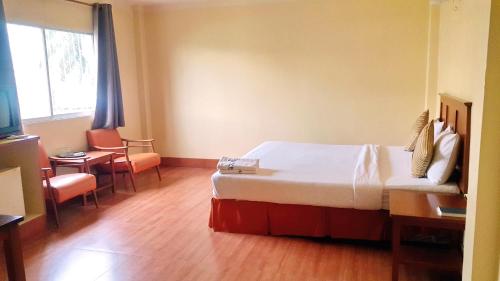 春蓬Sri Chumphon Hotel的一间带床、桌椅的酒店房间