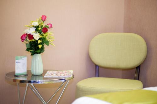 a vase of flowers sitting on a table next to a chair at Vivien's Hotel in Mactan