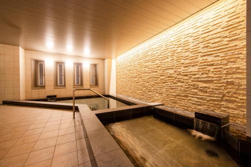 a pool of water in a room with a brick wall at karaksa hotel grande Shin-Osaka Tower in Osaka