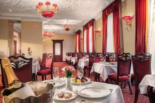 a restaurant with white tables and chairs and a chandelier at Staro Hotel in Kyiv