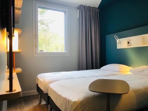 a hotel room with two beds and a window at ibis budget Reims Parc Des Expositions in Reims