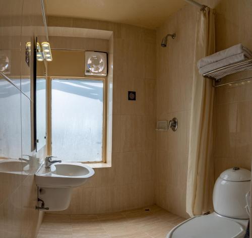 ein Bad mit einem Waschbecken, einem WC und einem Fenster in der Unterkunft Kathmandu Guest House by KGH Group in Kathmandu