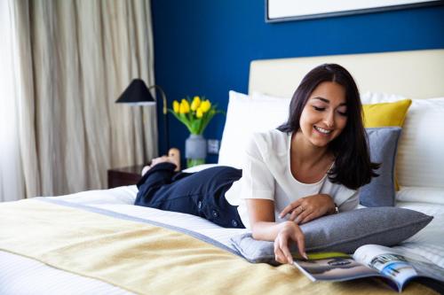 a woman sitting on a bed with a laptop at voco Dubai, an IHG Hotel in Dubai