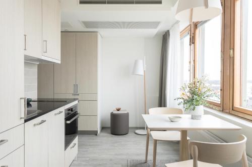 a kitchen with white cabinets and a table with chairs at Noli Sörnäinen in Helsinki
