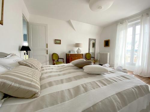 a white bedroom with a large bed with pillows at Les Chambres de LOUIS in Le Chesnay