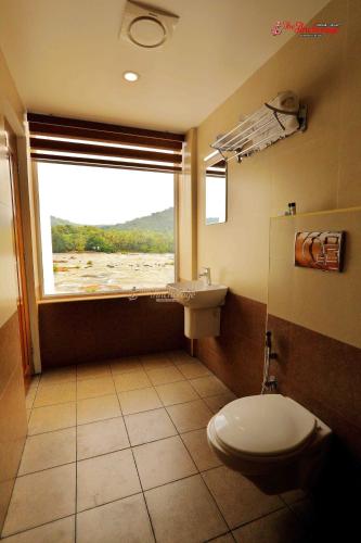 a bathroom with a toilet and a window at The Anchorage Athirapilly Resort in Athirappilly