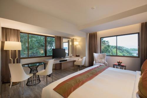 um quarto de hotel com uma cama e uma secretária com uma televisão em The Heritage Chiang Rai Hotel and Convention - SHA Extra Plus em Chiang Rai