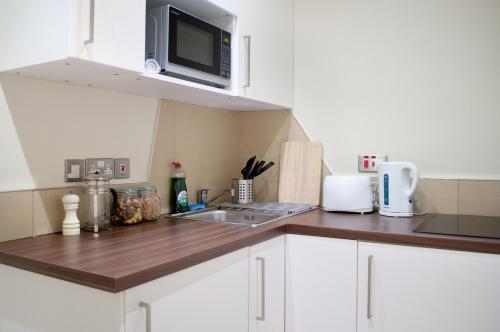 a kitchen with a sink and a microwave at Palmerston Suites in Edinburgh