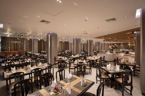 a restaurant with tables and chairs in a room at The Heritage Chiang Rai Hotel and Convention in Chiang Rai
