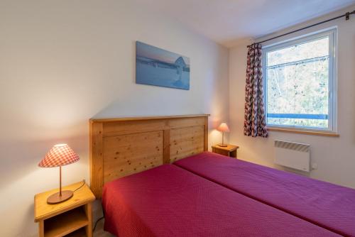 a bedroom with a bed with a red bedspread and a window at Appartement "L'Ostaloux" 6 personnes - Saint Lary Soulan in Vielle-Aure