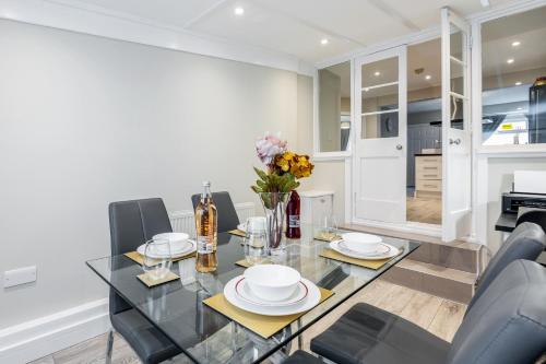 a dining room with a glass table and chairs at Dartford, Kent - Modern 2Bd 2Bath En-Suite Bungalow M25 Bluewater in Dartford