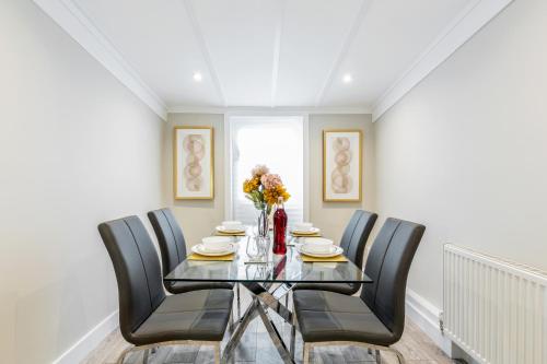 a dining room with a glass table and black chairs at Dartford, Kent - Modern 2Bd 2Bath En-Suite Bungalow M25 Bluewater in Dartford