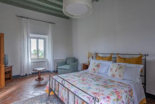 a bedroom with a bed and a chair and a window at Castello Di Meleto in Gaiole in Chianti