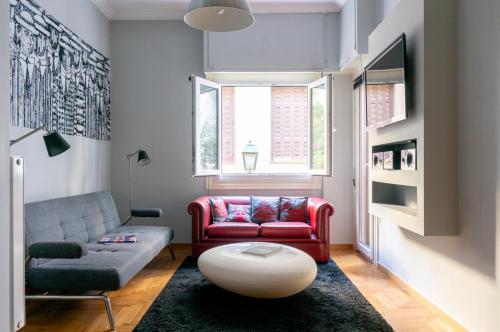 uma sala de estar com um sofá e uma cadeira vermelha em The Burton Luxury 1BR in Plaka, Athens em Atenas