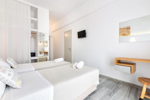 a white room with two beds and a tv at Golden Beach Hotel in Chrissi Akti