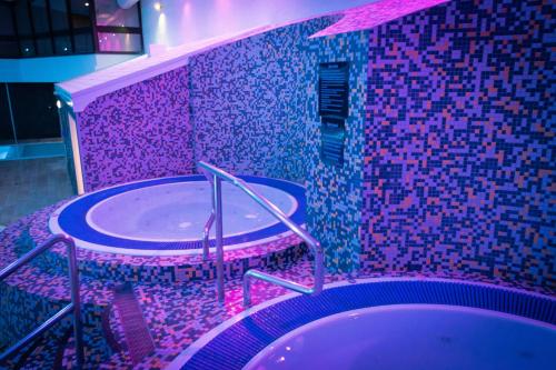 a bathroom with a sink and a tub with purple tiles at Village Hotel Wirral in Bromborough