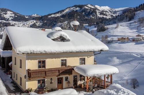 a house covered in snow with mountains in the background at Schaidreithof in Grossarl