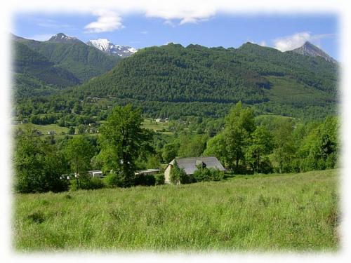 a house in a field with mountains in the background at Gîte des Moulins - Val d'Azun Pyrénées in Arcizans-Dessus