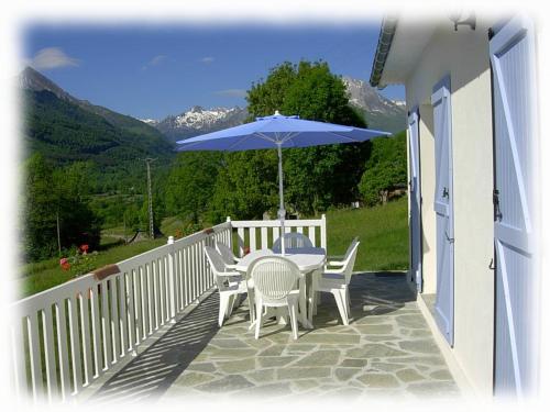 a table and chairs with an umbrella on a porch at Gîte des Moulins - Val d'Azun Pyrénées in Arcizans-Dessus