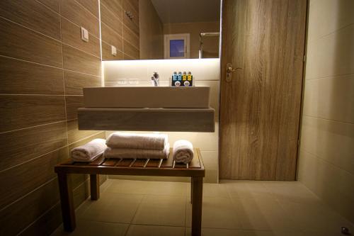 ein Badezimmer mit einem Waschbecken und Handtüchern auf einem Tisch in der Unterkunft La Place Suites - La Place De La Gare in Thessaloniki