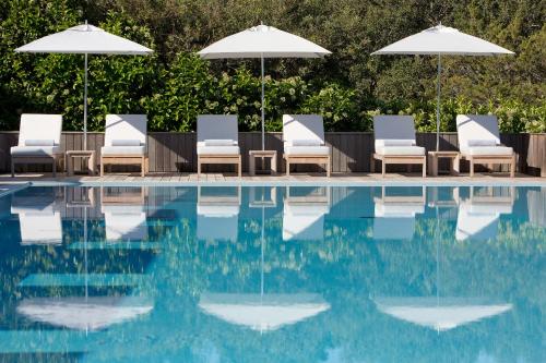 a group of chairs and umbrellas next to a swimming pool at Casadelmar in Porto-Vecchio