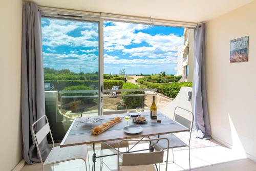 une salle à manger avec une table et une grande fenêtre dans l'établissement La Comédie de Vanneau - L'Intermède, à Palavas-les-Flots