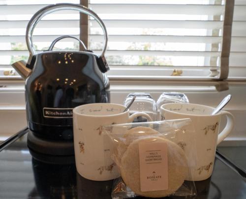 a tea kettle and four cups on a counter at The Roseate Villa Bath in Bath
